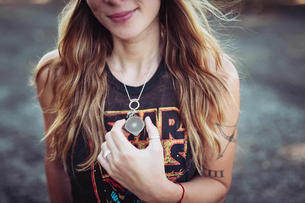 Woman holding Aires Flex environmental clarity pendant — wearable device supporting biological signaling coherence for quantum sensitive and electromagnetically complex environments.